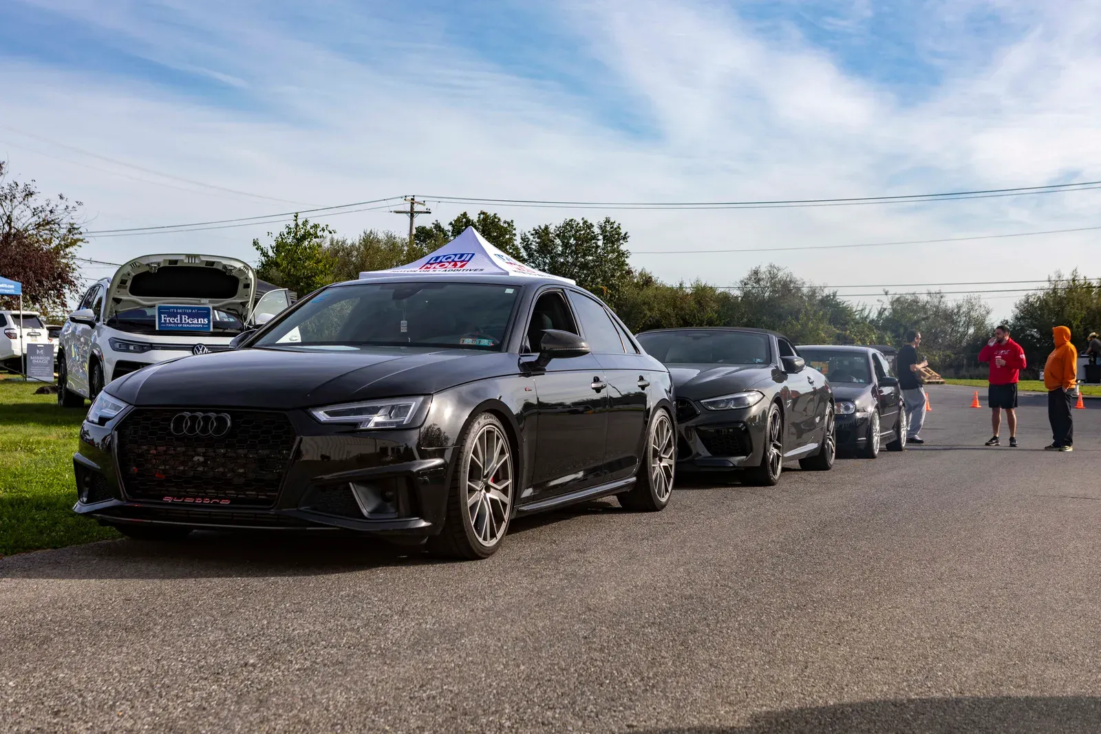 An Audi leads a line of cars near the vendor displays.