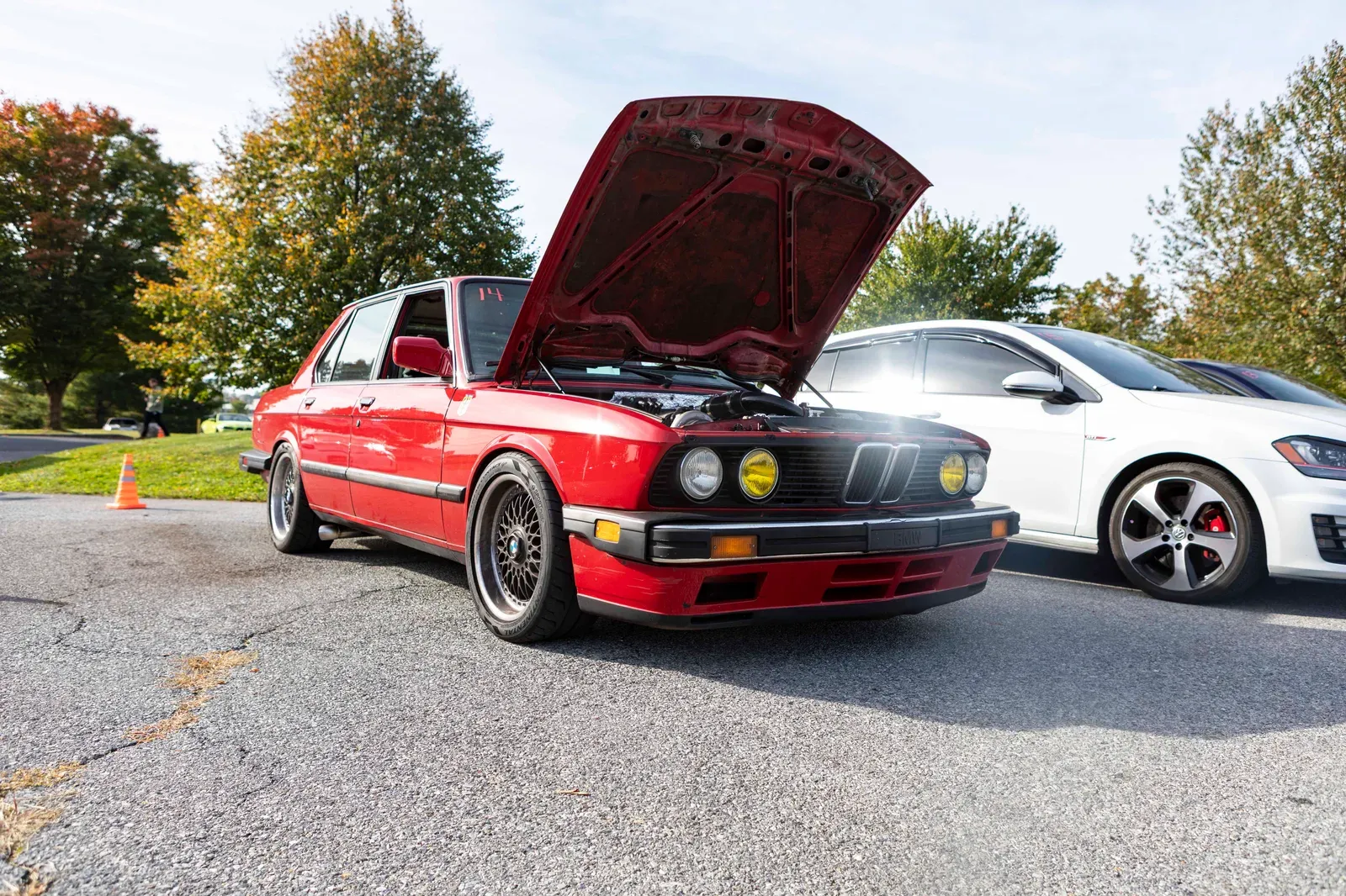 The red BMW with its hood open in the parking lot.